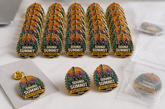 Bulk custom soft enamel pins by Bella Forge arranged in neat rows with a few loose pins in front on a clean desk scene